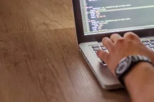 A digital marketing freelancer in Kollam focused on website development while typing on a laptop computer.